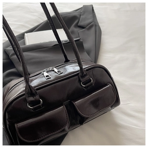 Detail of dark brown faux leather Boston bag featuring two front pockets and double zippers