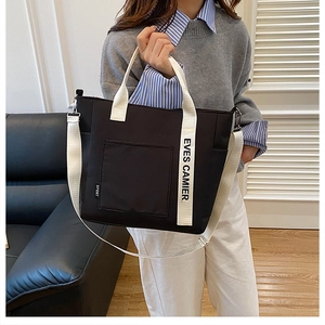 Detail of black nylon tote bag featuring white logo straps and adjustable shoulder strap