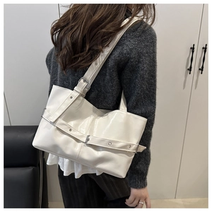 Detail of cream white tote bag with adjustable shoulder strap and silver metal buckle