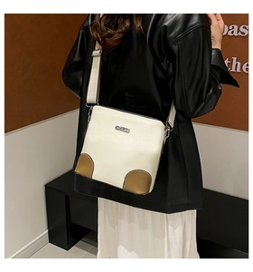 Detail of minimalist cream leather crossbody bag with brown base and wide woven strap