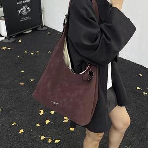 Large burgundy suede tote bag in minimalist Hobo style worn by a model in autumn street setting