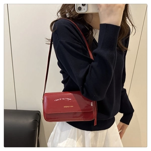 Close-up of vintage dark red patent leather shoulder bag with golden lettering detail