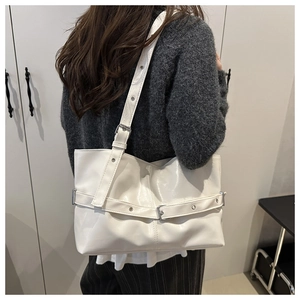 Detailed view of white large tote bag featuring silver buckle straps and glossy PU leather