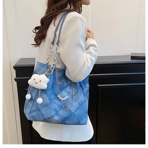 Detail of blue quilted denim tote bag with silver chain strap and cloud charm accessory