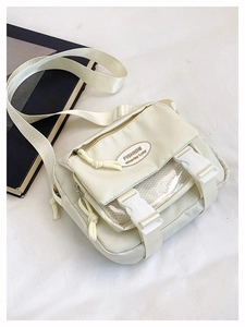 Detail of cream nylon crossbody bag featuring mesh pocket and plastic buckle closure