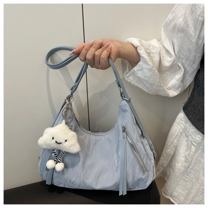 Detail of light blue hobo bag with front zippers and white cloud plush charm detail
