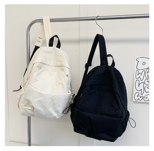 Close-up of minimalist nylon backpacks in white and black with drawstring side pockets