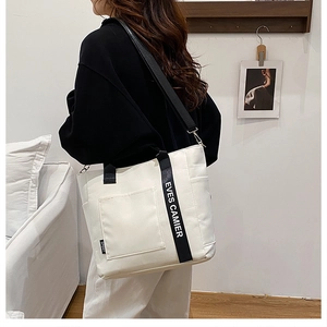 Detail of canvas bento tote bag showing adjustable strap and black handles on a model