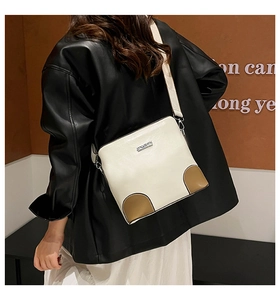 Detail of ivory crossbody bucket bag with brown patchwork and wide textile shoulder strap