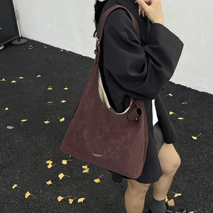 Deep burgundy large tote bag in matte suede leather styled with autumn ginkgo leaves