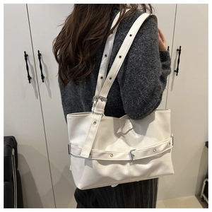 Close-up of a white leather tote bag with decorative buckle strap worn by a model