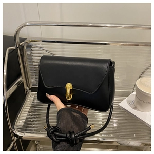 Detail of black leather shoulder bag with gold capsule clasp and knotted strap design