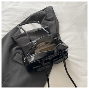 Detail view of glossy black shoulder bag interior showing spacious capacity and pocket