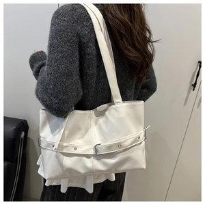 Detail of white leather tote bag with decorative buckle and polished metal hardware