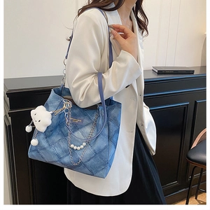 Detail of blue quilted tote bag with pearl chain decoration and plush cloud charm