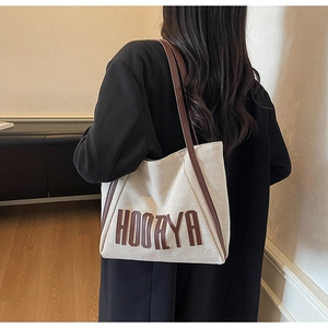 Side view of large off-white canvas tote bag with brown straps worn by a model