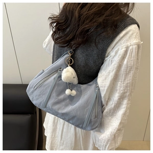 Light blue nylon crescent shoulder bag featuring silver zippers and white plush charm