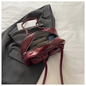 Detail view of burgundy glossy shoulder bag showing interior space with a wallet