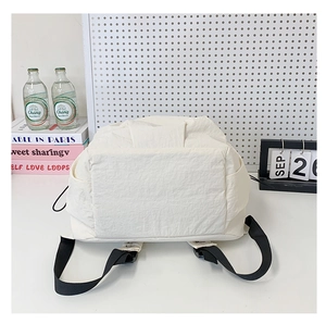 Detail view of the back straps and side pocket of the cream minimalist casual backpack