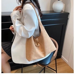 Dettaglio della borsa tote in pelle scamosciata caramello con logo oro e anello