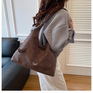 Dettaglio di una grande borsa tote in pelle scamosciata marrone scuro a tracolla