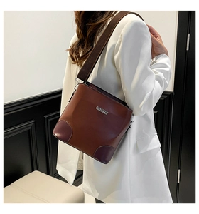Detail of dark brown leather bucket bag featuring purple reinforced corners and strap