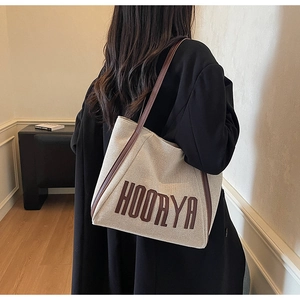 Detail of off-white canvas tote with brown leather straps and HOORYA lettering