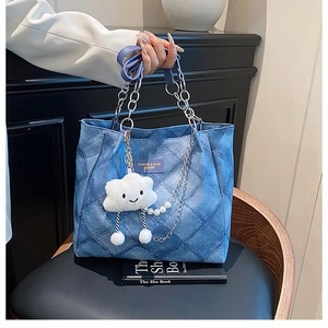 Close-up of quilted denim tote bag with silver chain, cloud charm, and pearl strap details