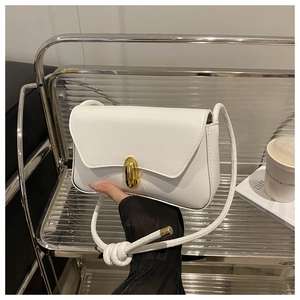Detail of white PU leather shoulder bag featuring a gold clasp and knot strap design