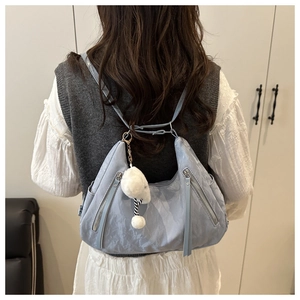 Detail of light blue wrinkled nylon crescent bag with plush ball and zipper pockets
