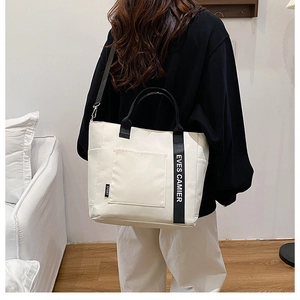 Detailed view of the large white canvas tote bag with adjustable shoulder strap on a model