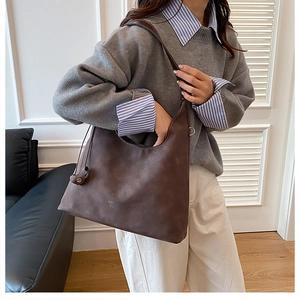 Dettaglio borsa tote in pelle scamosciata marrone scuro con logo e tracolla larga