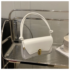 Detailed view of white leather shoulder bag with gold metal clasp and knotted handle detail