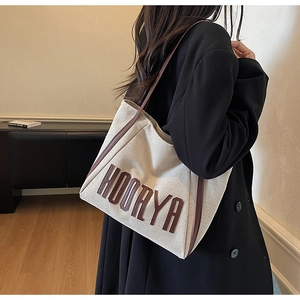 Detailed side view of HOORYA canvas tote bag with brown leather straps worn by model