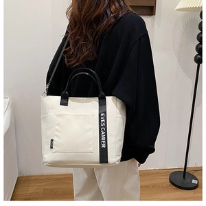 Canvas lunch tote bag with shoulder strap and side pocket worn by a person