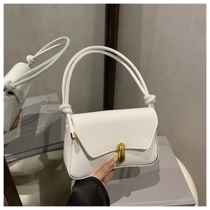 Detail of white leather shoulder bag featuring a golden oval clasp and knotted rope strap