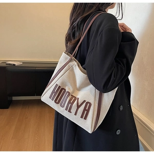 Detail of canvas tote bag with HOORYA lettering and dark brown leather straps