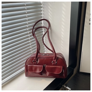 Detail view of burgundy shiny shoulder bag with double front pockets on windows