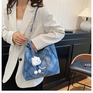 Detail of denim tote bag with quilted pattern, silver chain and pearl decoration