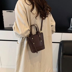 Sac seau marron foncé minimaliste avec clous dorés et bandoulière élégante chic