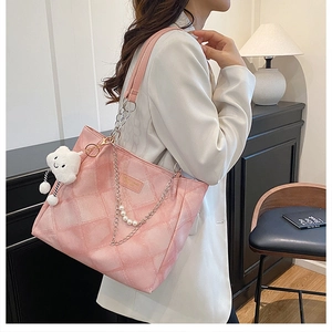 Detail showing pink quilted tote bag with pearl chain and cloud plush charm on a shoulder