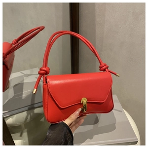 Close-up of red leather handbag featuring a gold twist lock and knotted strap detail