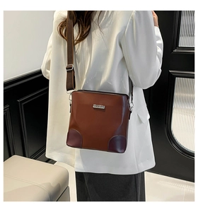 Detail view of a soft brown leather bucket bag with a wide nylon strap on a model