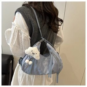 Close-up of light blue crescent hobo bag with cute white cloud plush pendant and silver zipper