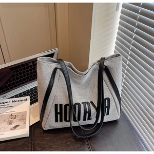 Close-up of large canvas tote bag with black leather straps and HOORAYA print