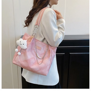 Detail of pink checkerboard tote bag featuring pearl chain strap and plush cloud charm