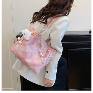 Detail of pink quilted tote bag with pearl chain strap and plush cloud charm on model