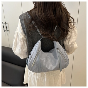 Detail of light blue hobo bag showing soft wrinkled leather texture and silver zippers