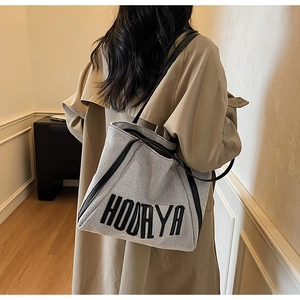 Detail of a canvas tote bag with black leather trim and HOORYA lettering for women
