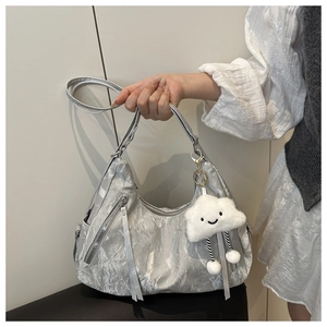 Detail of silver pleated tote bag with metallic texture, tassel zipper and plush charm